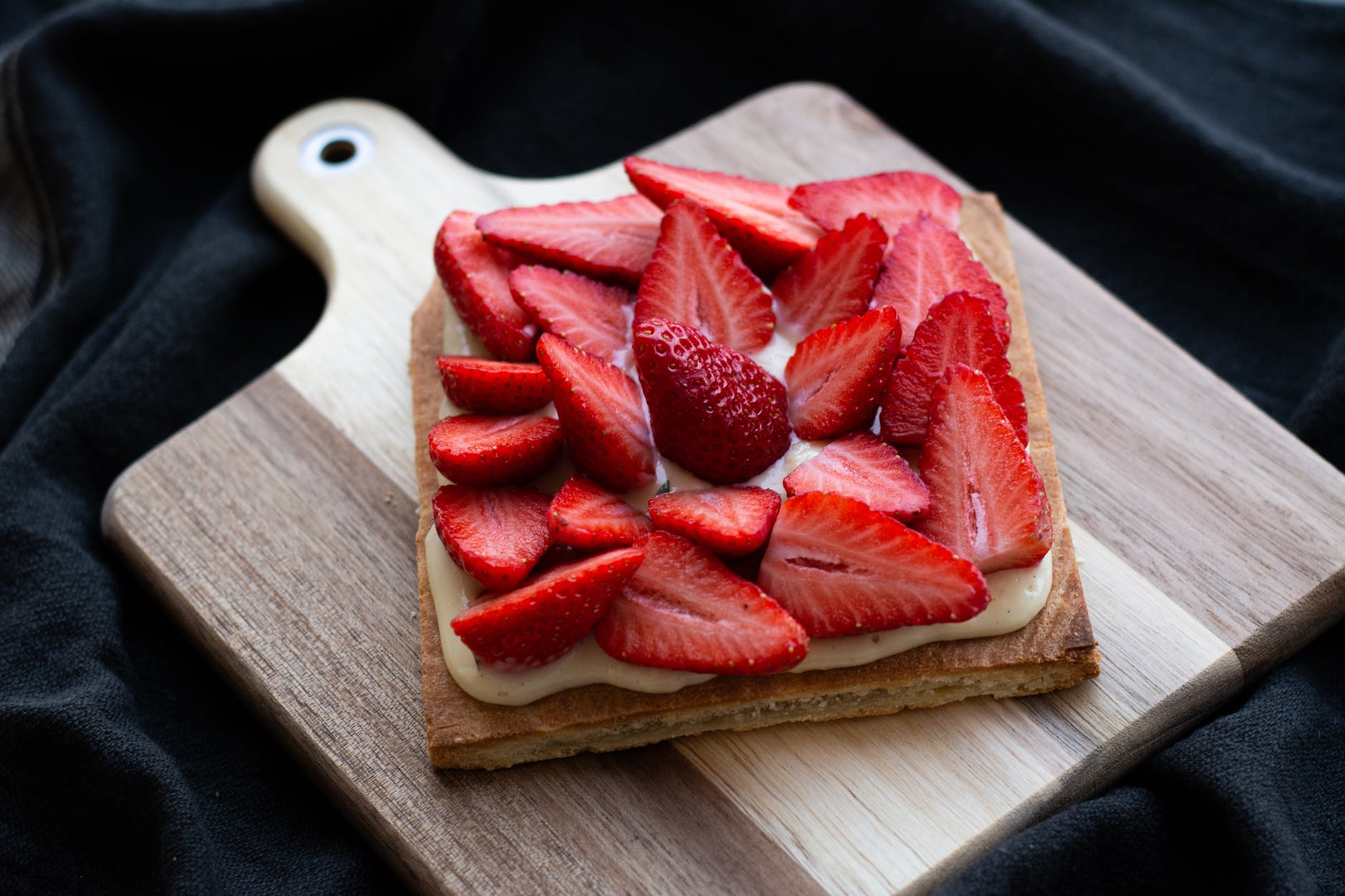 sliced strawberries over squared bread on wooden tray