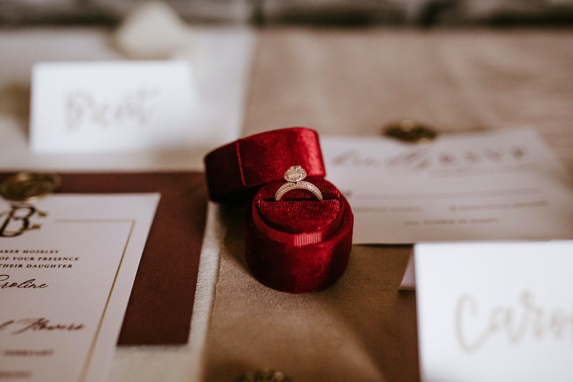 red box with golden ring placed on table with invitation cards