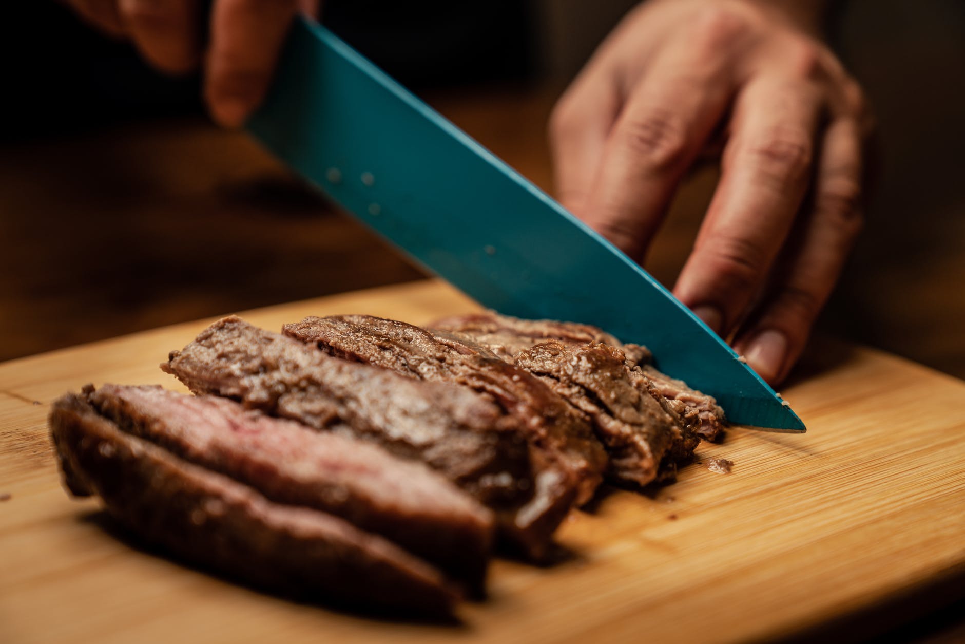 person slicing chocolate cake on green chopping board