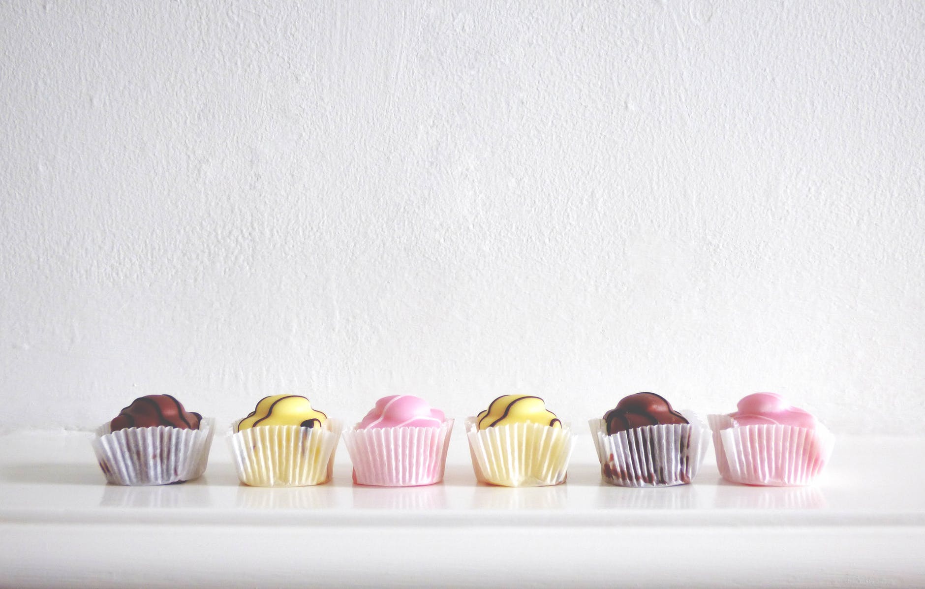 six cupcakes near white wall